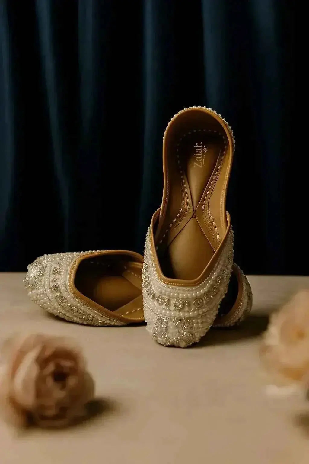 Elegant pearl-embellished juttis with intricate embroidery, perfect for bridal or festive occasions.