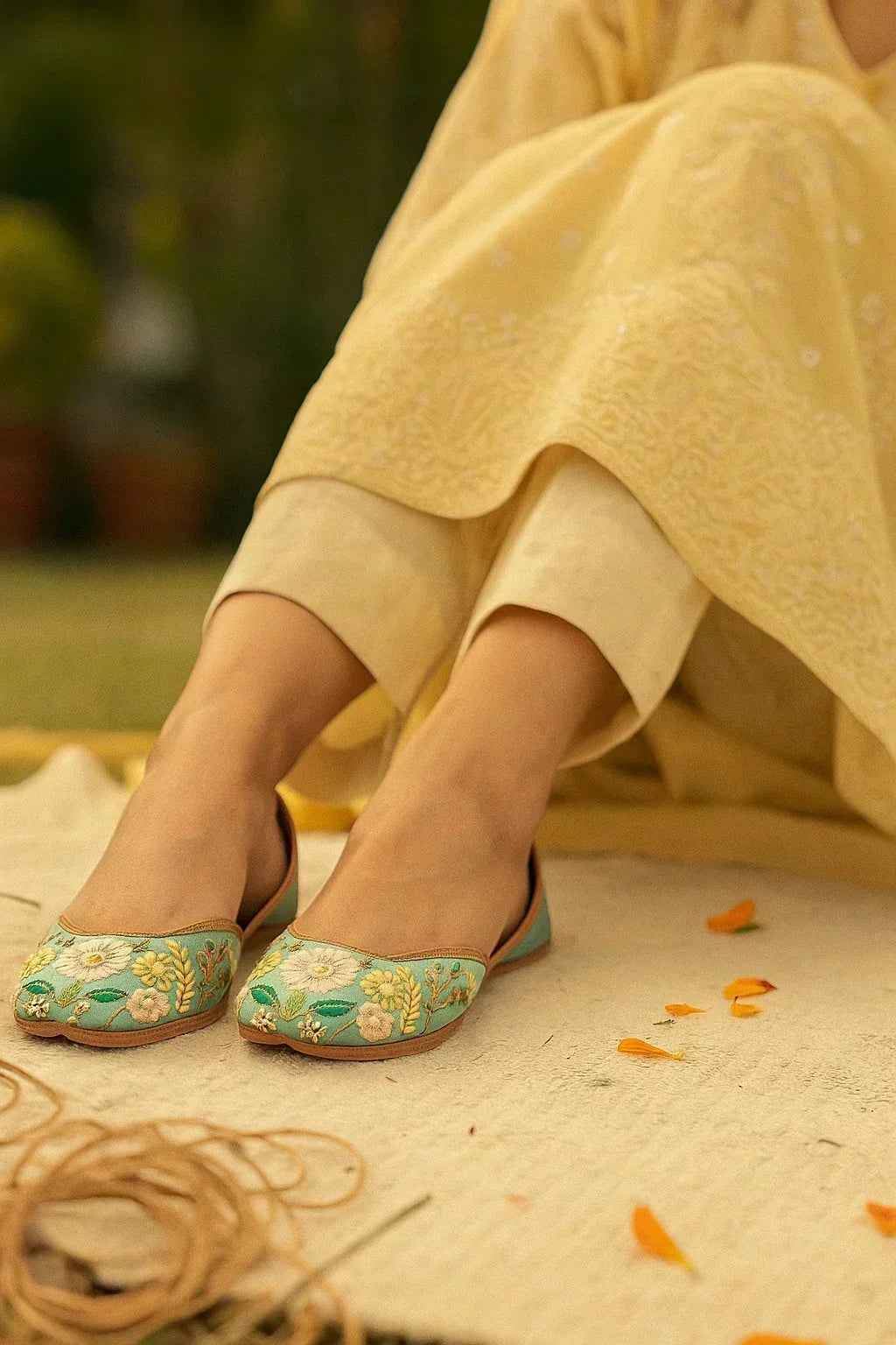Handcrafted floral embroidered juttis in mint green, paired with yellow ethnic wear, perfect for romantic occasions.