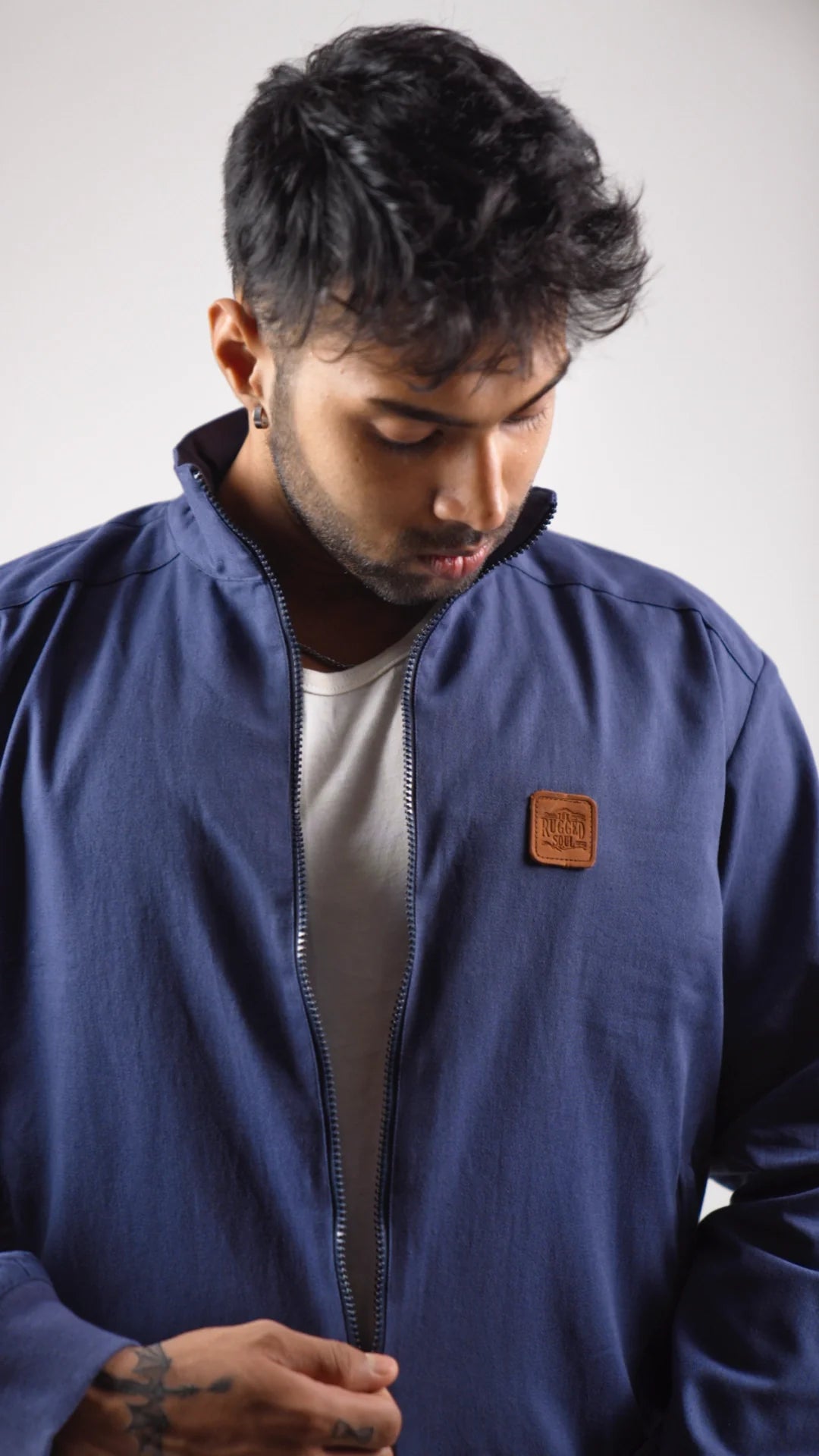 Man wearing a blue jacket with a brown patch on a white background