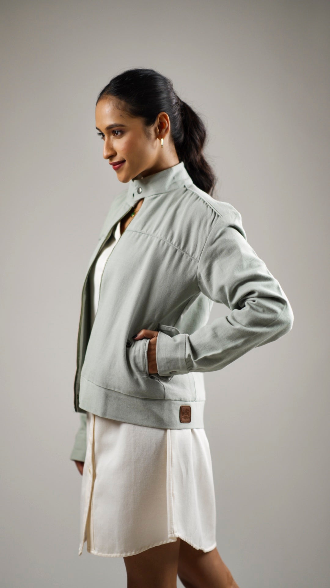 Woman posing in an olive sage coloured cotton canvas jacket with welt pockets