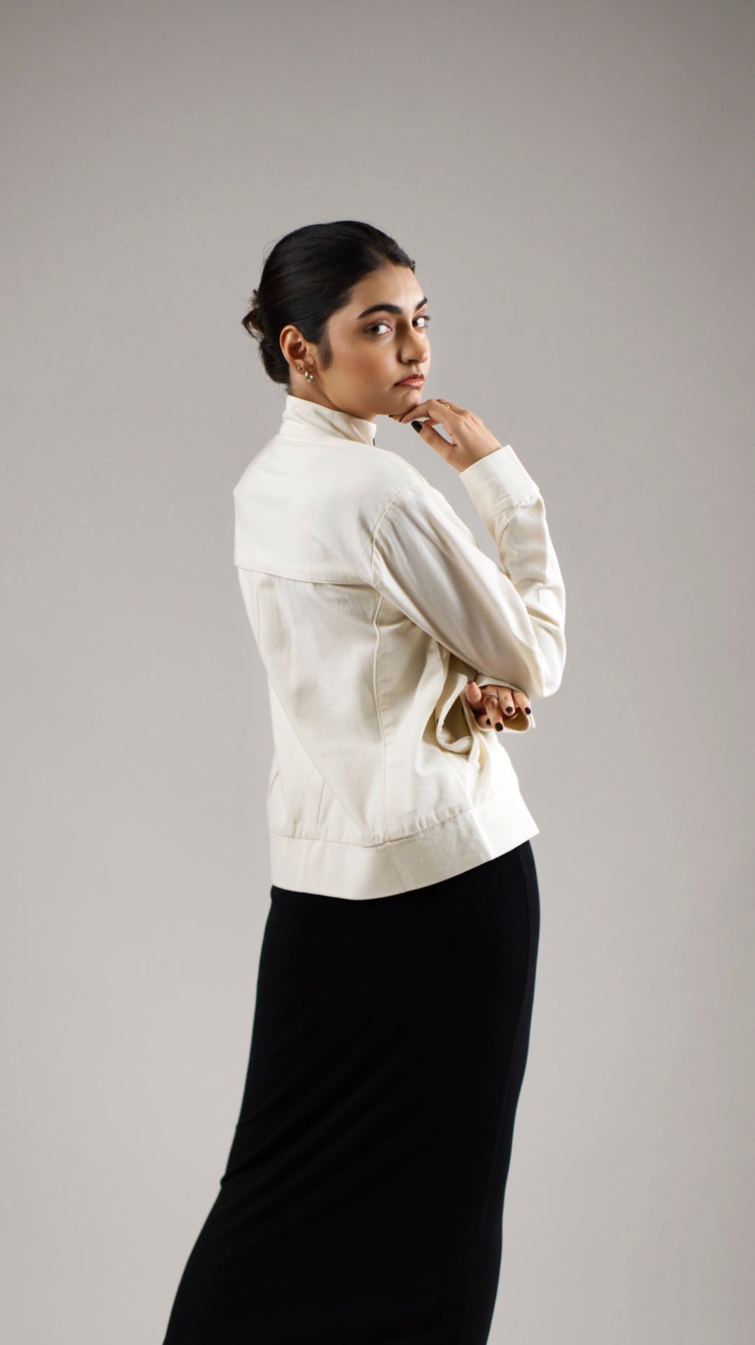 Back view of a woman wearing a white coloured cotton canvas jacket over a dark skirt