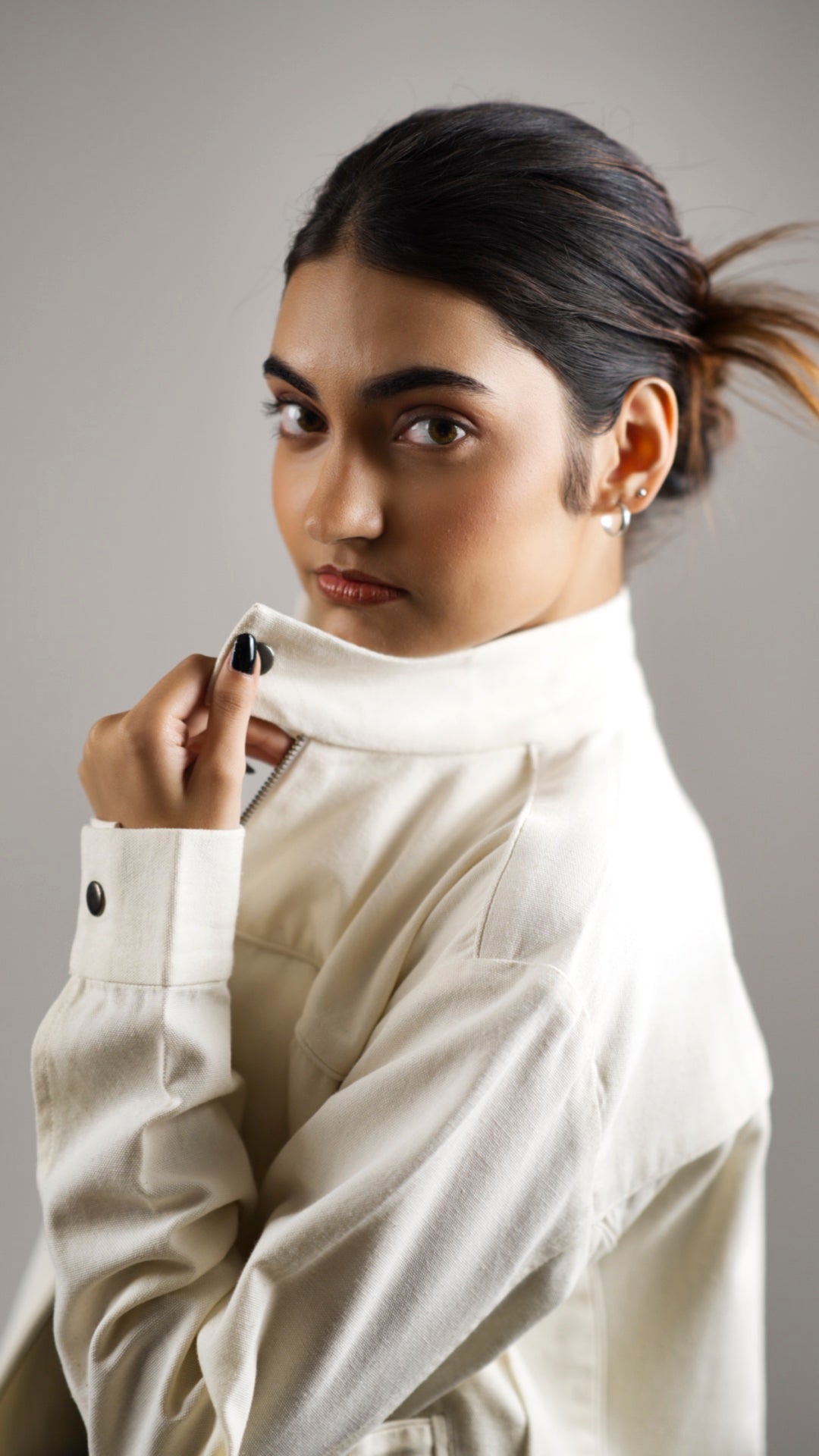 Closeup of a woman wearing a white coloured cotton canvas jacket over a dark skirt