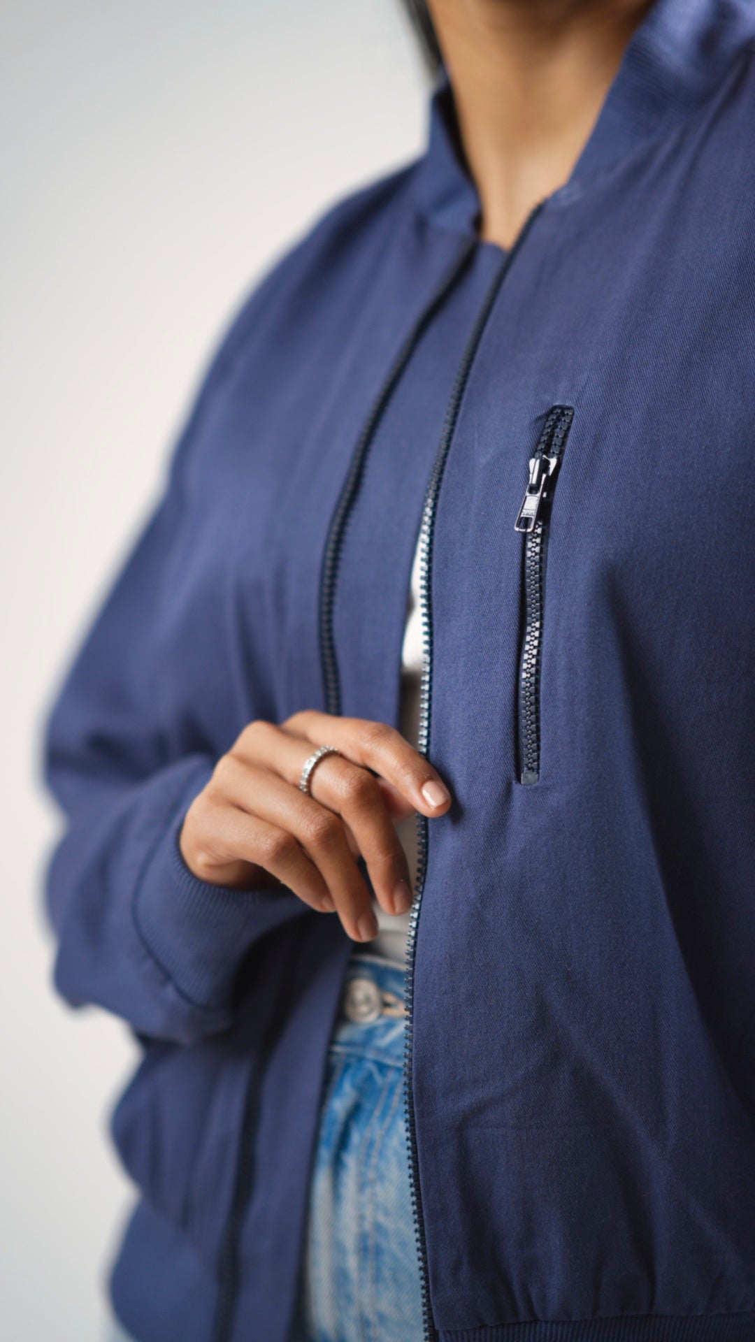 Closeup of a steel blue cotton twill jacket showing the external zipper on the front