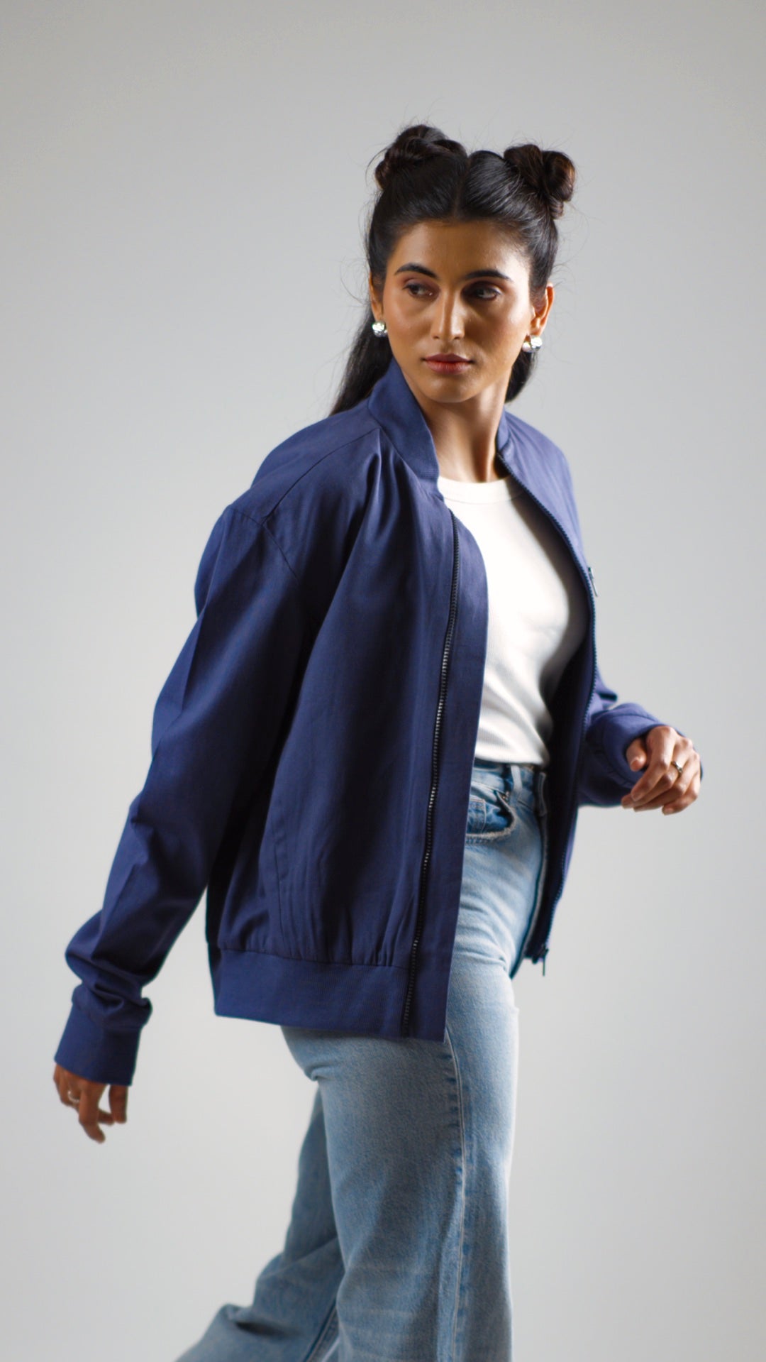 Woman posing in a steel blue cotton twill jacket worn above light coloured denim jeans