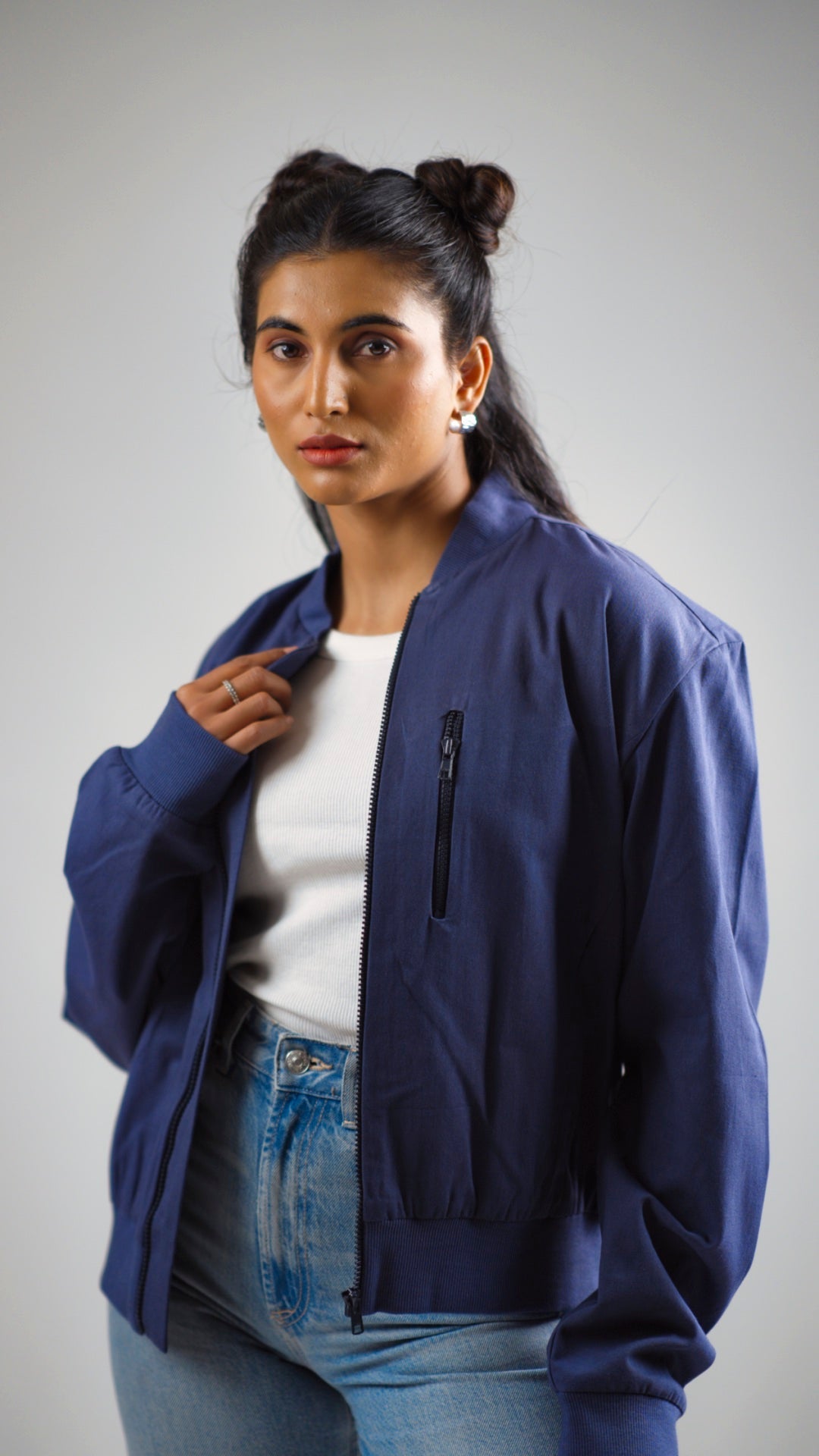 Woman posing in a steel blue cotton twill jacket worn above light coloured denim jeans